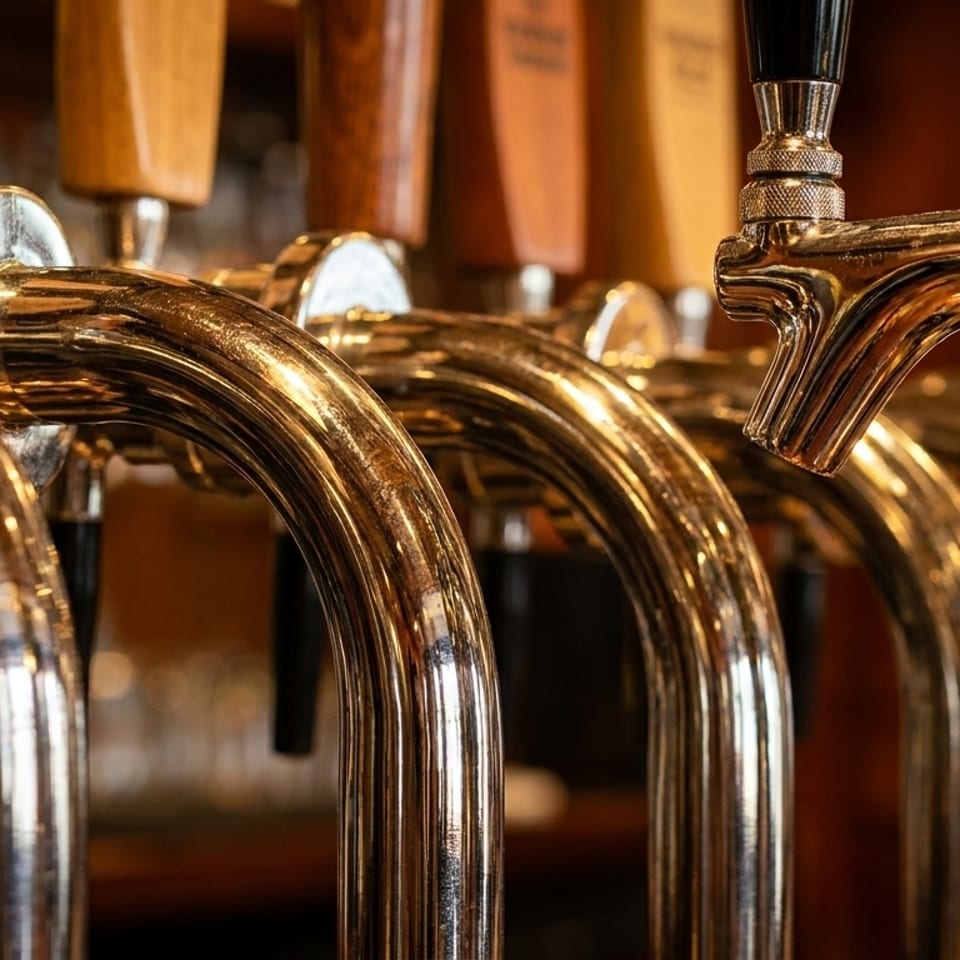 Close-up of multiple shiny brass beer taps with wooden and black handles in a row.